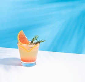 verre de cocktail qui est avec une tranche d'agrume et brin de romarin