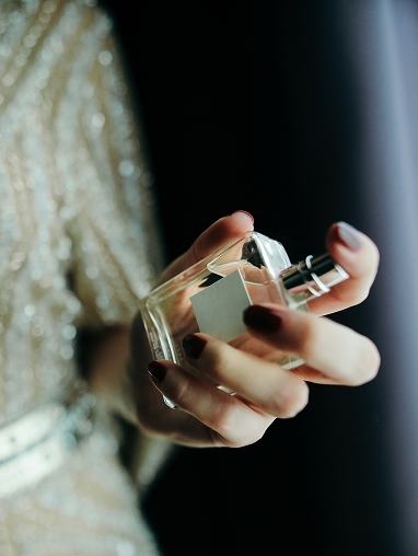 One hand holds a perfume bottle and perfumes itself