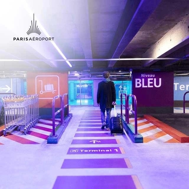 Un homme marche avec sa valise cabine dans un parking officiel Paris Aéroport