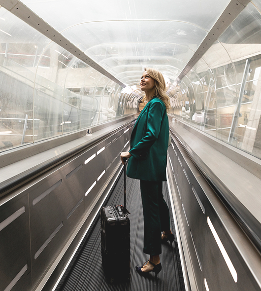 Woman with her suitcase on the airport moving walkway