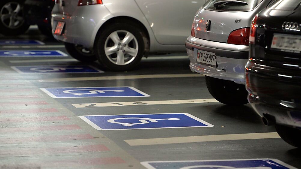 Voitures stationnées dans un parking pour personne à mobilité réduite