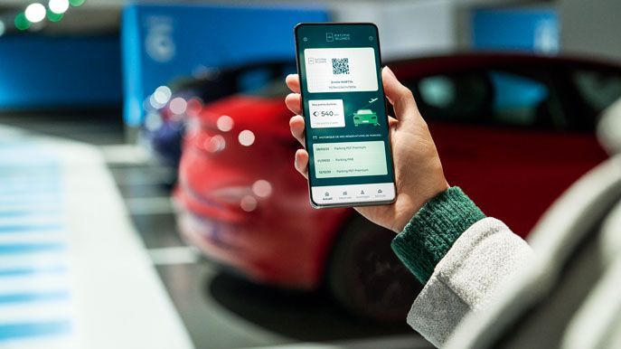 Une personne montre sa carte de fidélité Extime Rewards sur son téléphone dans un parking Officiel Paris Aéroport